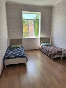 two beds in a room with a window at Gunluk ev in Sheki +11 photos