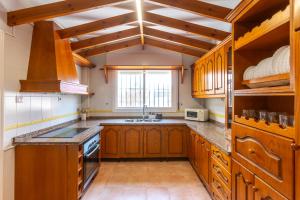 a large kitchen with wooden cabinets and a window at house las chuchas CALAHONDA in Motril