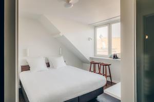 un lit blanc dans une chambre avec une fenêtre dans l'établissement ROMY BRUGES Historic Centre, à Bruges
