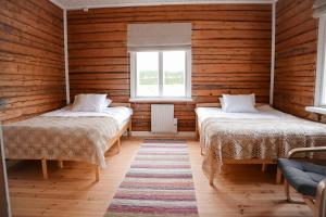 two beds in a room with wooden walls at Villa Onni in Kauhajoki