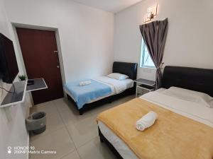 a hotel room with two beds and a television at Arkid 10 Guesthouse in Ipoh
