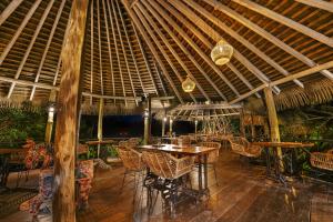 a restaurant with tables and chairs and a wooden ceiling at Huma Terra Lodges in Hikkaduwa