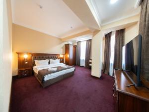 a hotel room with a bed and a flat screen tv at Grand Capital Hotel in Tashkent