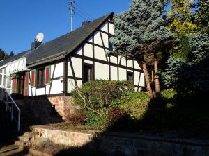 ein Schwarz-Weiß-Haus mit einem Baum davor in der Unterkunft vakantiehuis Hunsrück in Leisel