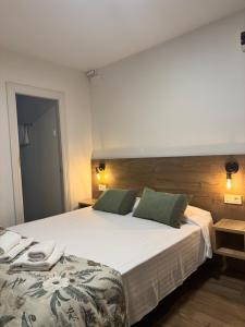 a bedroom with a large bed with white sheets and green pillows at IRUÑA ROOMs in Pamplona