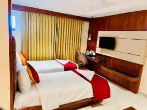 a hotel room with two beds and a flat screen tv at Sri Vishnu Grand in Vellore