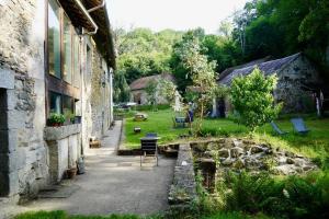 an old stone building with a yard with chairs and tables at Le Moulin de St André in Saint-André-en-Morvan