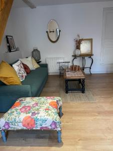 a living room with a green couch and a table at Le cottage à la glycine - Maison de charme au cœur des gorges de la Loire in Chambles