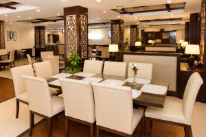 a dining room with a table and white chairs at Royalton Hotel Rawalpindi in Rawalpindi