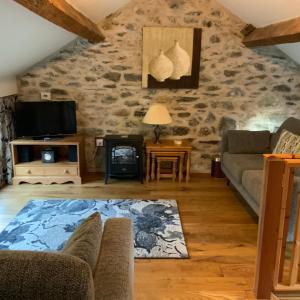 a living room with a stone wall at Tithe Barn 2 - Abercelyn Cottages - Llanycil - Bala - Gwynedd - LL23 7YF - UK in Llanycil