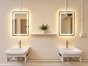 two sinks in a bathroom with two mirrors at Commune Lane Guesthouse, George Town in George Town