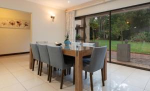 a dining room with a wooden table and chairs at Mancave Luxury Homes in Alberton +1 photo