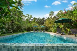 a swimming pool with two chairs and an umbrella at Huma Terra Lodges in Hikkaduwa