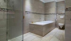 a bathroom with a tub and a toilet and a shower at Mancave Luxury Homes in Alberton
