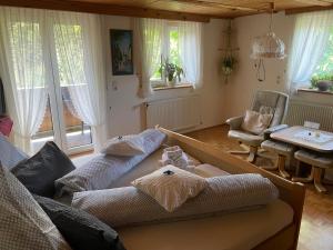 a living room with two couches and a table and windows at Gästehaus Möschel in Weiler-Simmerberg
