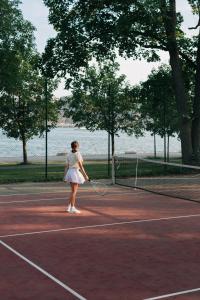 a woman standing on a tennis court holding a racket at Hotel Skeppsholmen, Stockholm, a Member of Design Hotels in Stockholm