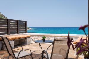 a patio with a table and chairs and the ocean at Aura Seafront Villa in Neo Itilo