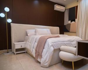 a bedroom with a large white bed with a chair at Capediem luxury apartment in Oba Ile