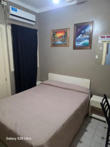 a small bedroom with a bed and a window at Hotel Roy's in San Juan