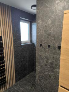 a bathroom with a stone shower with a window at Dubrowes cottage in Bobrów