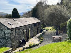 a stone house with a picnic table and a bench at Tithe Barn 2 - Abercelyn Cottages - Llanycil - Bala - Gwynedd - LL23 7YF - UK in Llanycil