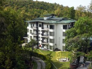 a large white building with a green roof at Ataraxia by Alivaa , Mussoorie Foothills, Dehradun in Dehradun
