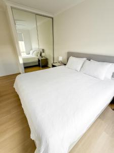 a large white bed in a room with a mirror at The Sierra in Dunsborough