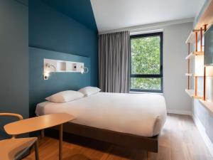 a room with a bed and a table and a window at ibis budget Rouen Centre Rive Gauche in Rouen
