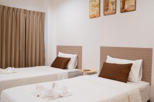two beds in a hotel room with white sheets at JT Place Buriram in Buriram +64 photos