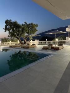 a pool with benches and umbrellas next to a building at Villa RESA - Intero allogio in Orikum