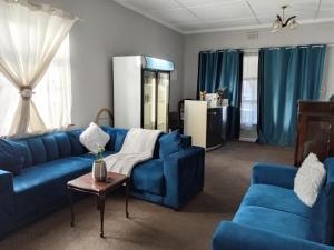 a living room with blue couches and a table at Great Choice BnB in Goodwood
