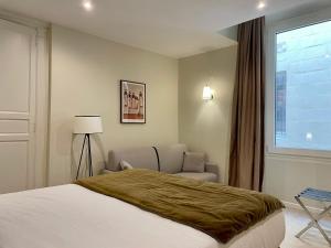 a bedroom with a bed and a chair and a window at Hôtel du Théâtre - Hypercentre - Climatisé in Bordeaux