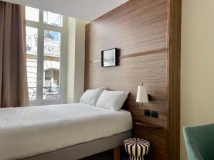 a hotel room with a bed and a window at Hôtel du Théâtre - Hypercentre - Climatisé in Bordeaux