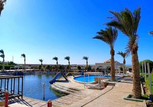 a swimming pool with palm trees and a slide at DaVinCi hotel in Hurghada