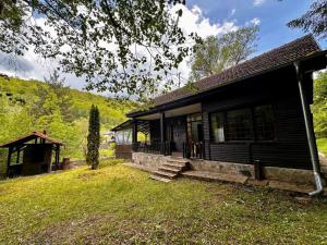 a black house with a porch and a grass yard at Weekend House in Vrelo in Jelovica