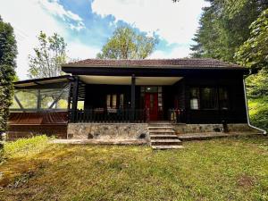 a small house with a red door in the grass at Weekend House in Vrelo in Jelovica