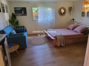 a bedroom with a large bed and a blue couch at LE RUBINJO 2 in Saint-Benoît