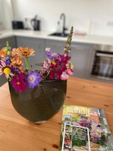 a vase filled with flowers on a table next to a magazine at Ferien in der Flurstraße in Velbert +7 photos