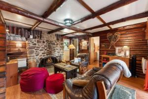 a living room with a leather couch and a stone fireplace at Spa Nature & Mountain - Le Pinacle in Frelighsburg