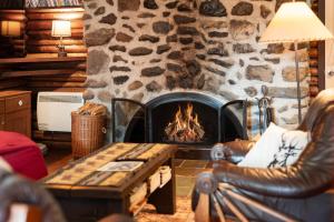 a living room with a stone fireplace with a couch and a table at Spa Nature & Mountain - Le Pinacle in Frelighsburg