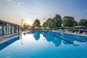 a large swimming pool with chairs and umbrellas at Hotel Narcisa in Veržej