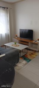 a living room with a table and a flat screen tv at 1 bedroom BNB Meru in Meru