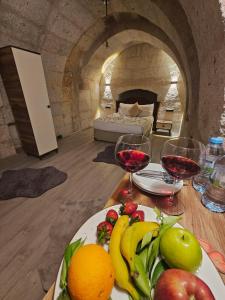 a table with a plate of fruit and wine glasses at novela in stone house in Uçhisar