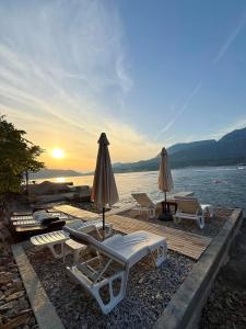 a group of lounge chairs and umbrellas on a beach at Ivanović smeštaj in Rose