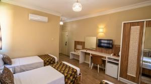 a hotel room with two beds and a television at Grand Gülizar Otel in Urfa