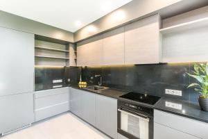 a kitchen with white cabinets and black counter tops at Imanta Garden Townhouses in Riga +38 photos