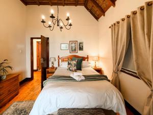 a bedroom with a large bed and a chandelier at Far Niente Beachfront Guesthouse in Wilderness