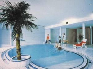 a large swimming pool with a palm tree in a building at Appartement mit All inklusive Angebot und Pool in Runding