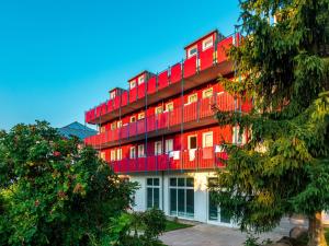 a red building with balconies on the side of it at Appartement mit All inklusive Angebot und Pool in Runding