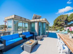 a glass house with blue furniture on a deck at Playa de Muro Chalet with Pool for 6 in Playa de Muro